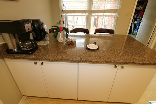 kitchen featuring white cabinetry and dark stone counters