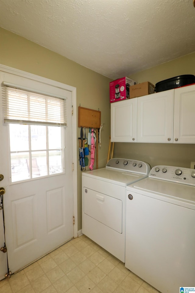 laundry area featuring washing machine and clothes dryer, cabinet space, a textured ceiling, and light floors