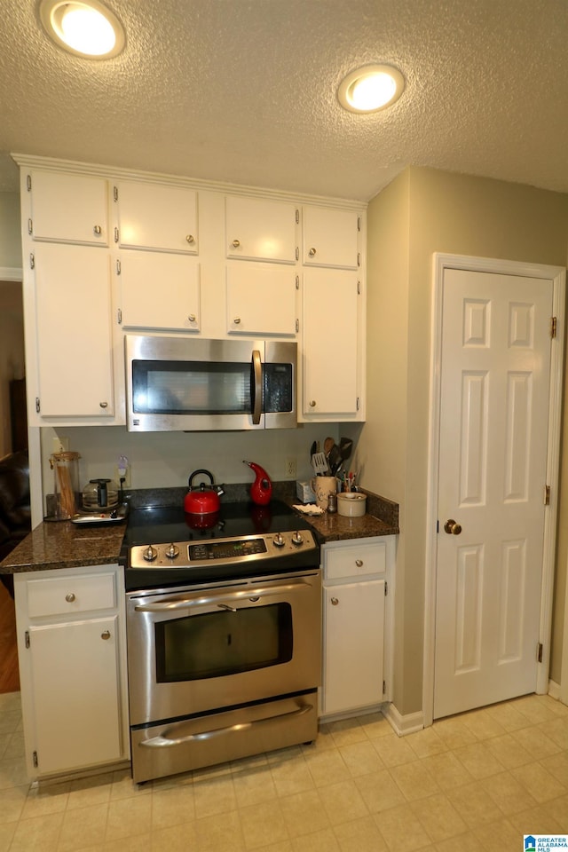 kitchen featuring dark stone countertops, stainless steel appliances, a textured ceiling, and white cabinetry