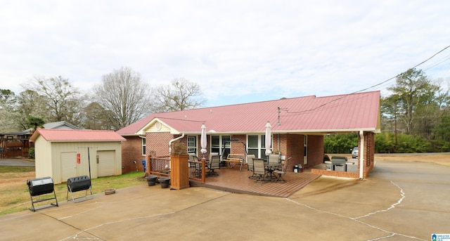 rear view of house with brick siding, a wooden deck, metal roof, an outdoor structure, and a storage unit