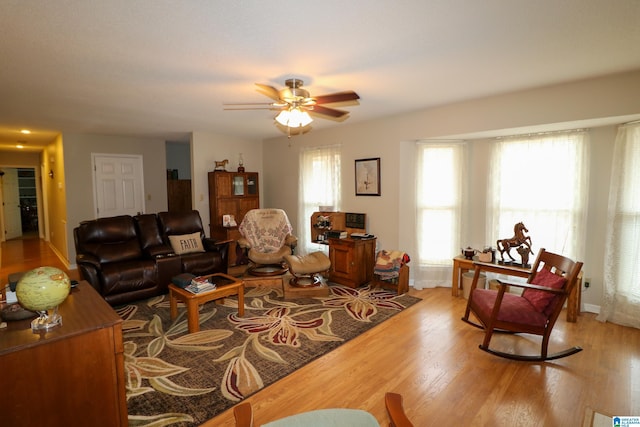 living area featuring baseboards, light wood-style floors, and a ceiling fan