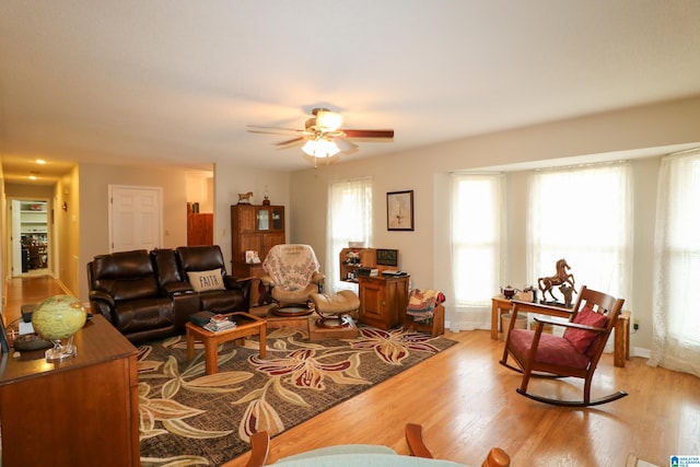 living room featuring a wealth of natural light, baseboards, ceiling fan, and light wood finished floors