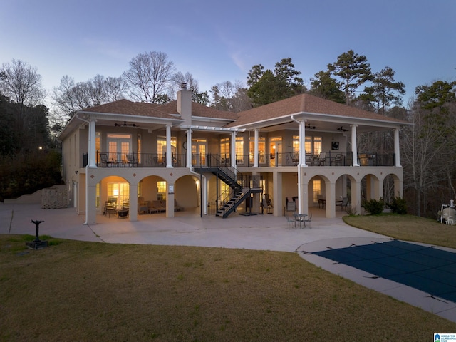 back of property with ceiling fan, stairs, a chimney, a balcony, and a patio area