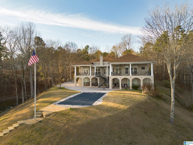 exterior space with stairs, a patio, a yard, and a chimney