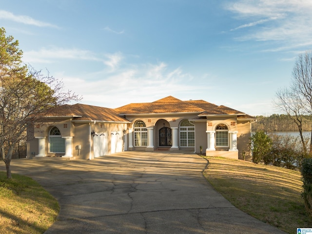 mediterranean / spanish home with a water view, a garage, driveway, and stucco siding