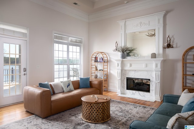 living area with visible vents, wood finished floors, a high end fireplace, and ornamental molding