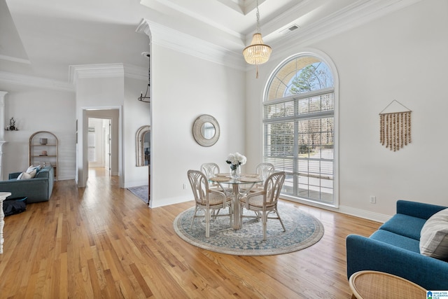 dining space with visible vents, baseboards, a chandelier, ornamental molding, and light wood-style floors