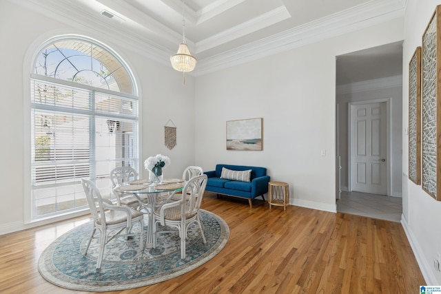 dining room featuring light wood-style flooring, baseboards, visible vents, and ornamental molding