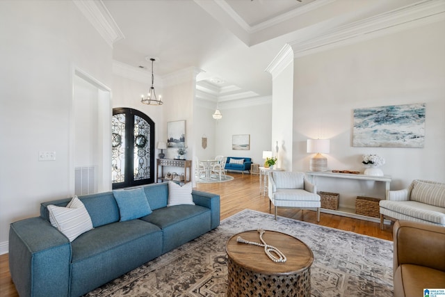 living room featuring wood finished floors, visible vents, french doors, crown molding, and a chandelier