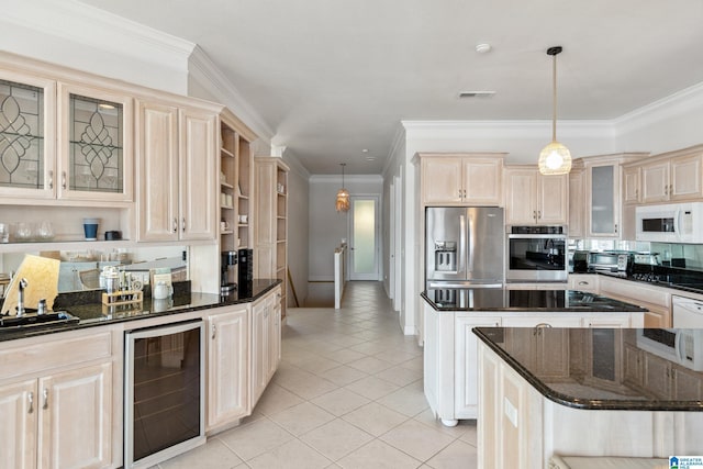 kitchen featuring visible vents, a kitchen island, beverage cooler, stainless steel appliances, and a sink