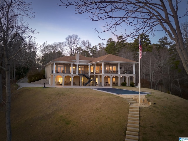 rear view of house with stairway, a lawn, driveway, and a patio area