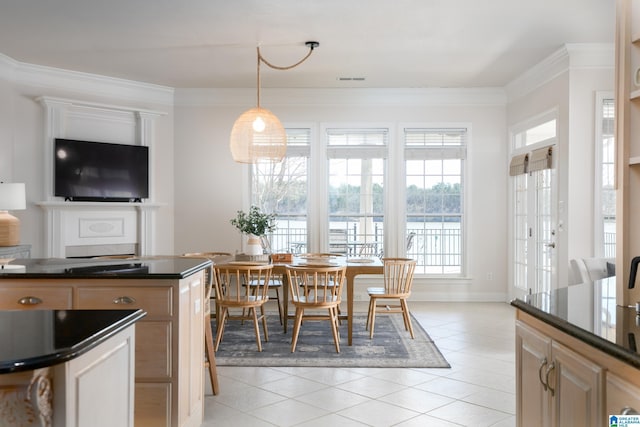 kitchen with dark countertops, light tile patterned floors, decorative light fixtures, and ornamental molding