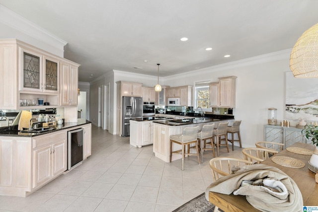 kitchen featuring dark countertops, a kitchen bar, light tile patterned flooring, stainless steel appliances, and a sink