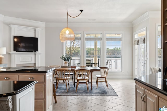 kitchen with plenty of natural light, dark countertops, light tile patterned flooring, and crown molding