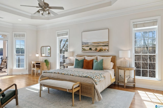 bedroom featuring access to outside, crown molding, a tray ceiling, and wood finished floors