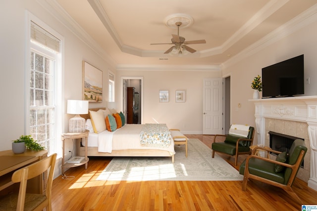 bedroom featuring a raised ceiling, multiple windows, and wood finished floors