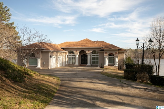 mediterranean / spanish-style home featuring a garage, driveway, and stucco siding