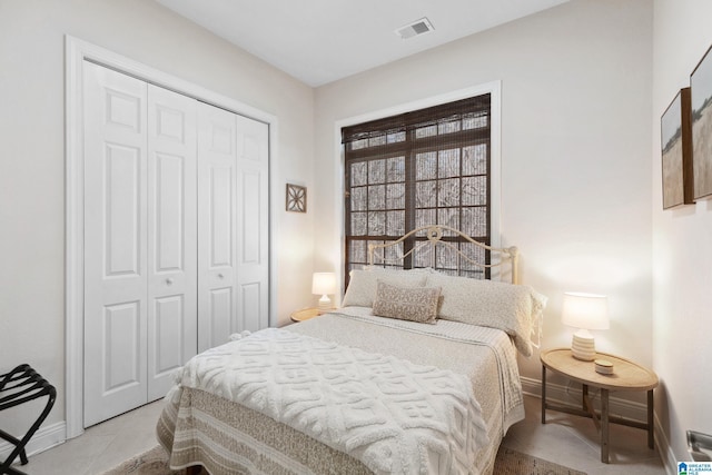 bedroom with visible vents, baseboards, a closet, and light tile patterned flooring