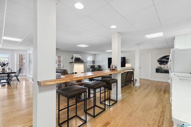 kitchen featuring light countertops, a kitchen breakfast bar, light wood-style floors, and a drop ceiling