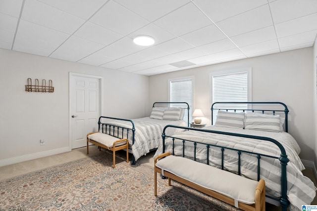 carpeted bedroom with baseboards and a drop ceiling