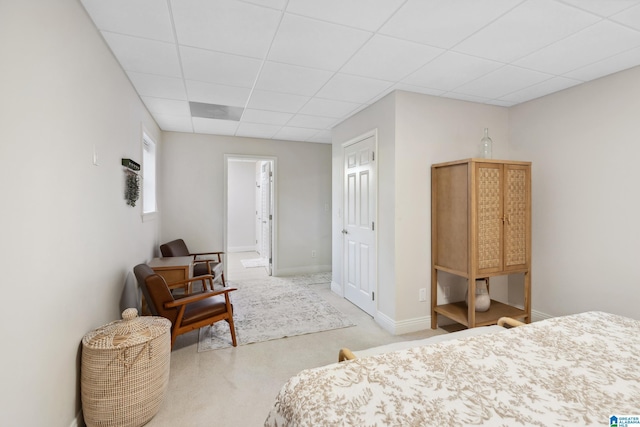 carpeted bedroom with a drop ceiling, ensuite bath, and baseboards