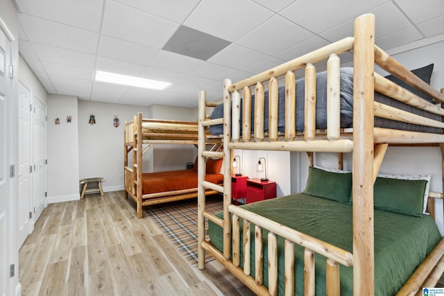 bedroom with wood finished floors, baseboards, and a drop ceiling