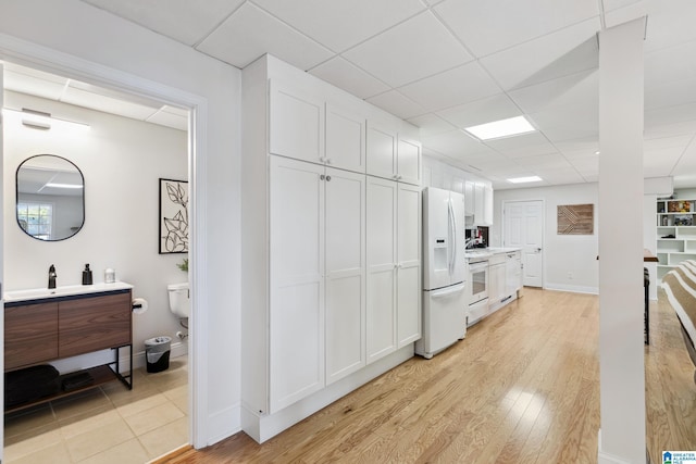 kitchen featuring white cabinetry, light wood-style flooring, range, and white fridge with ice dispenser