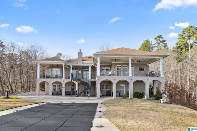 back of house with a patio, stairway, a balcony, ceiling fan, and a chimney