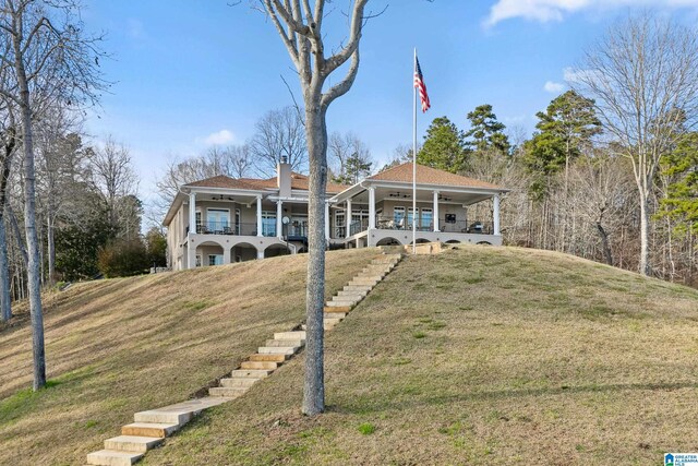 view of front of property with a front yard, a chimney, and a ceiling fan