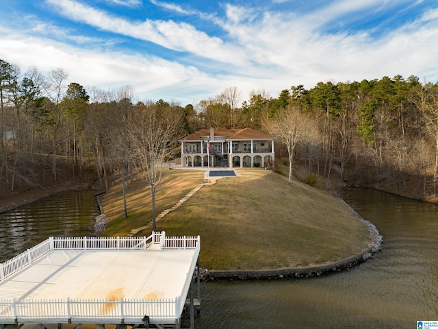 dock area featuring a yard, a water view, a wooded view, and fence