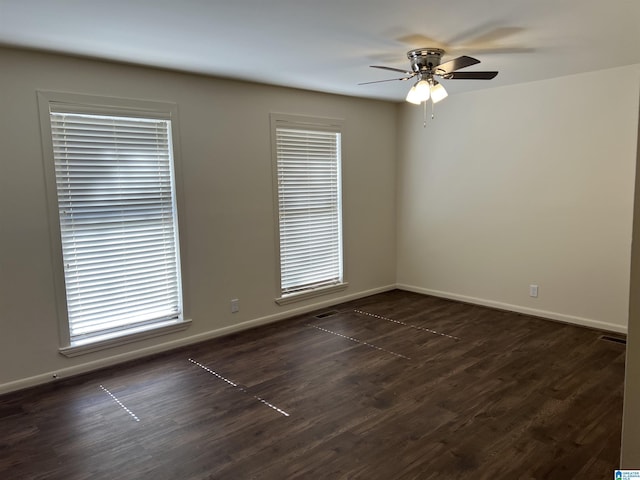 empty room featuring ceiling fan, baseboards, and dark wood-style floors