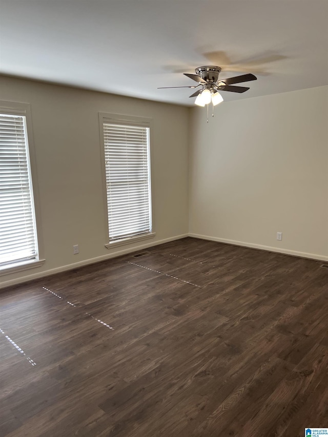 empty room with baseboards, dark wood-style flooring, and ceiling fan