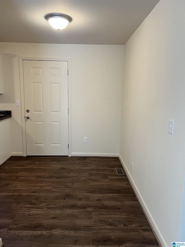 unfurnished room featuring dark wood-style floors, visible vents, and baseboards