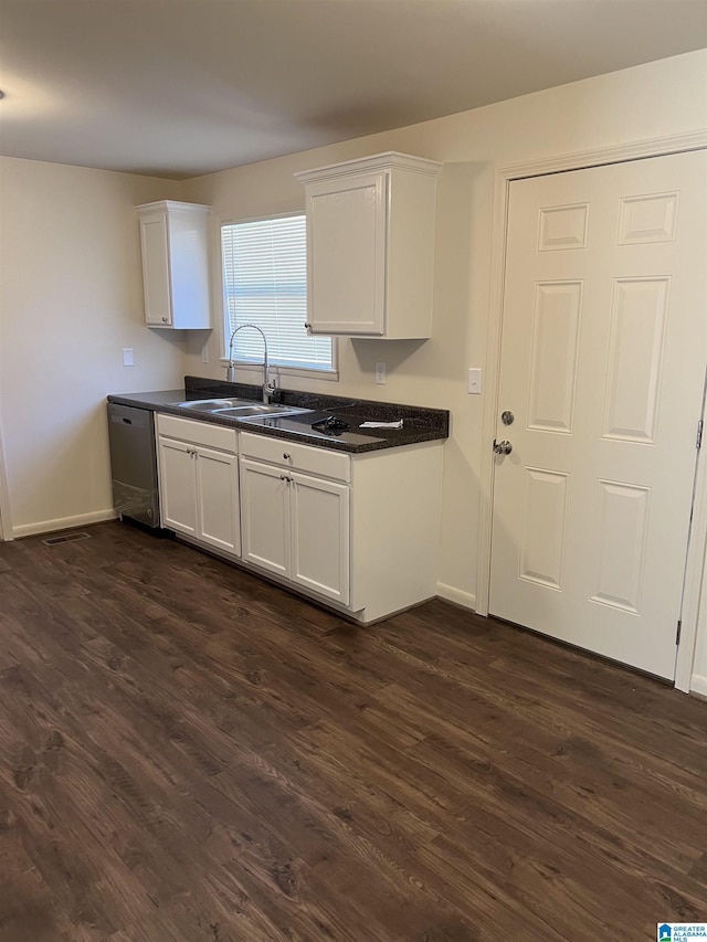 kitchen with dark countertops, dark wood-style floors, stainless steel dishwasher, and a sink