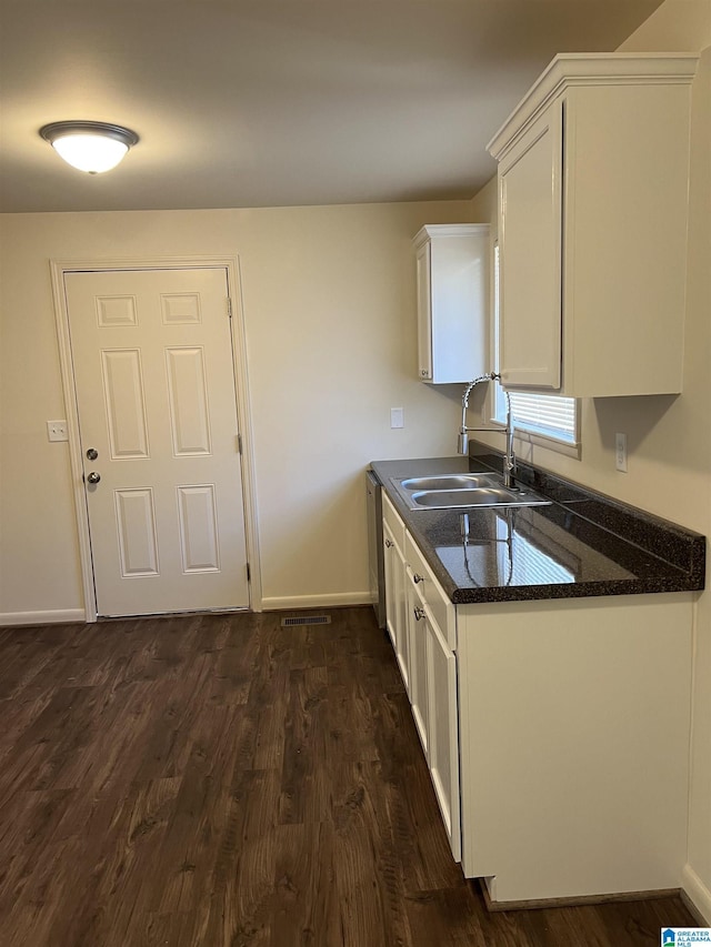 kitchen featuring dark wood-type flooring, white cabinets, baseboards, and a sink