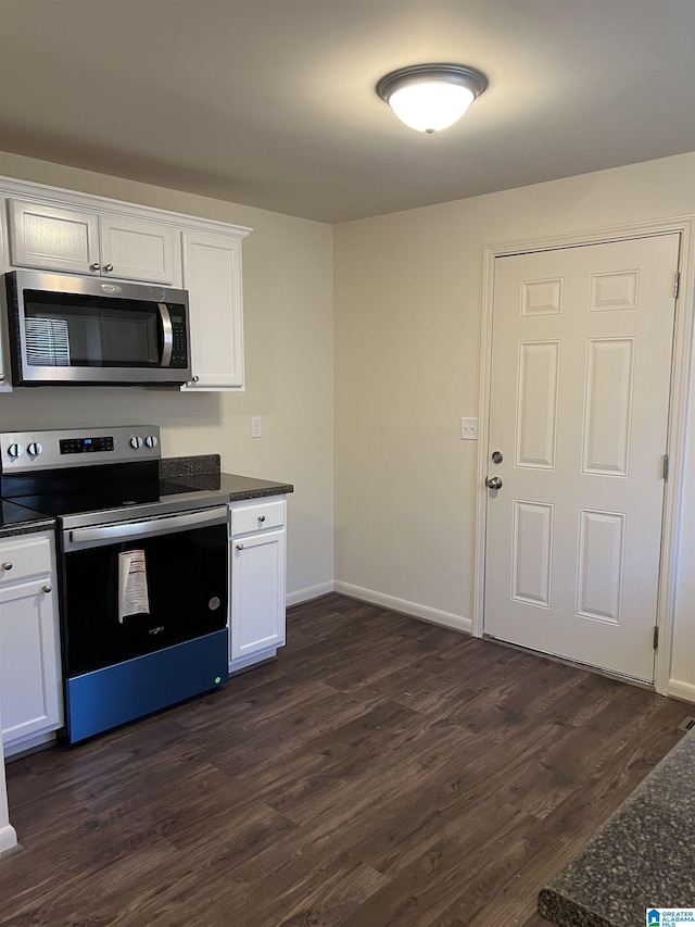 kitchen with dark wood-style floors, appliances with stainless steel finishes, white cabinetry, and baseboards