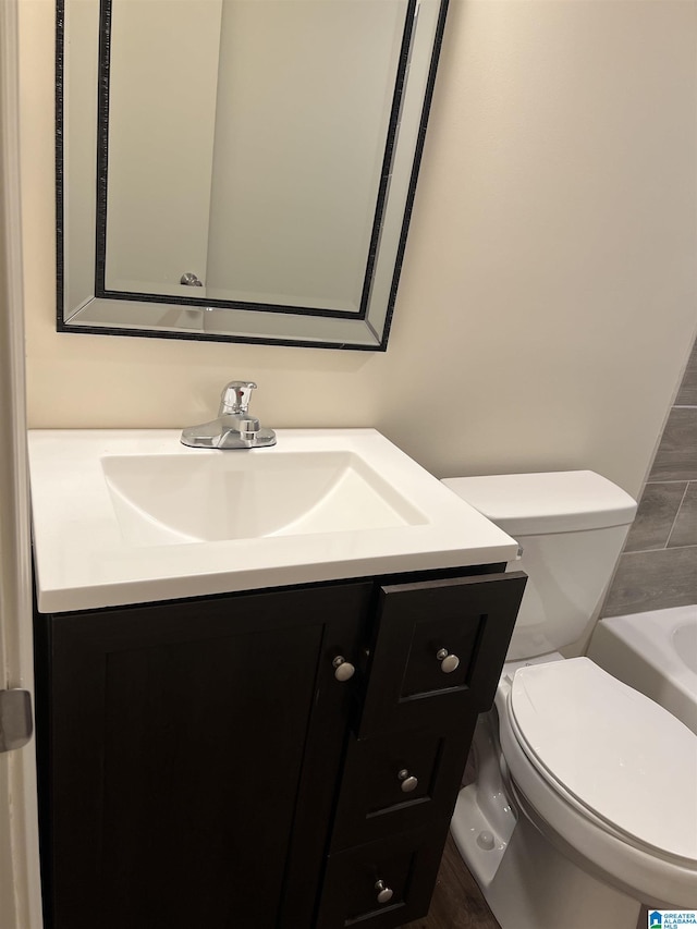 bathroom featuring a bathing tub, toilet, and vanity