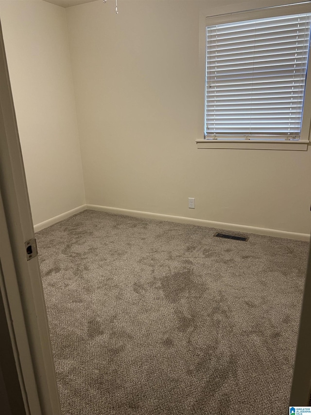 carpeted empty room featuring baseboards and visible vents