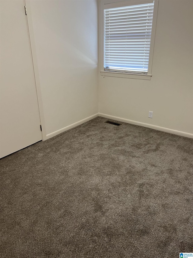 carpeted spare room with visible vents and baseboards