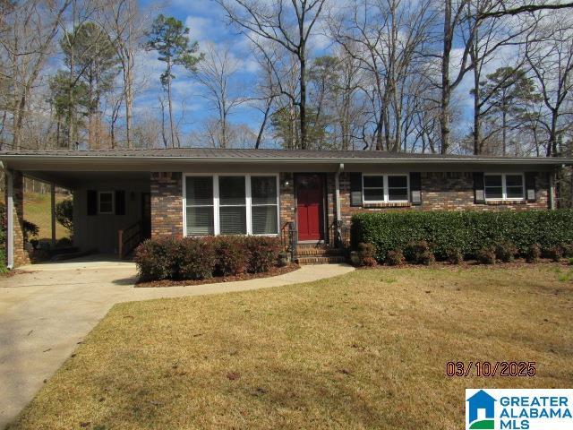 ranch-style home featuring a front yard, a carport, brick siding, and driveway