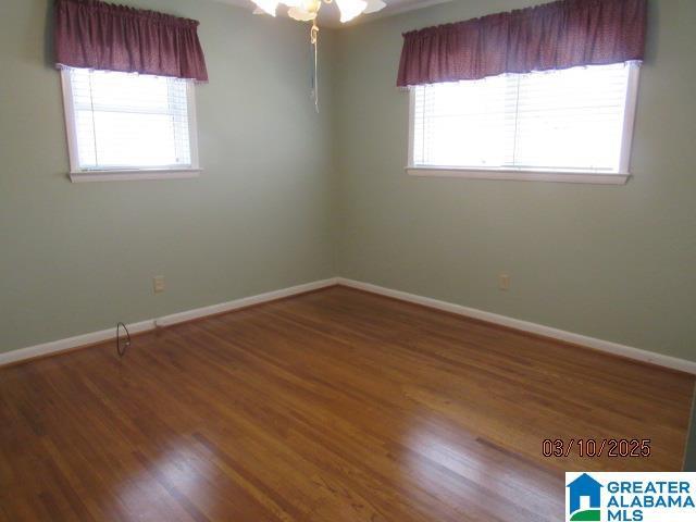 unfurnished room featuring a wealth of natural light, baseboards, and wood finished floors