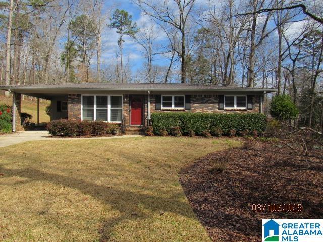 view of front of house featuring brick siding, an attached carport, driveway, and a front lawn