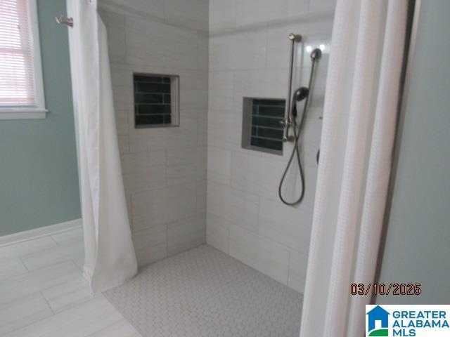 bathroom with baseboards and a tile shower