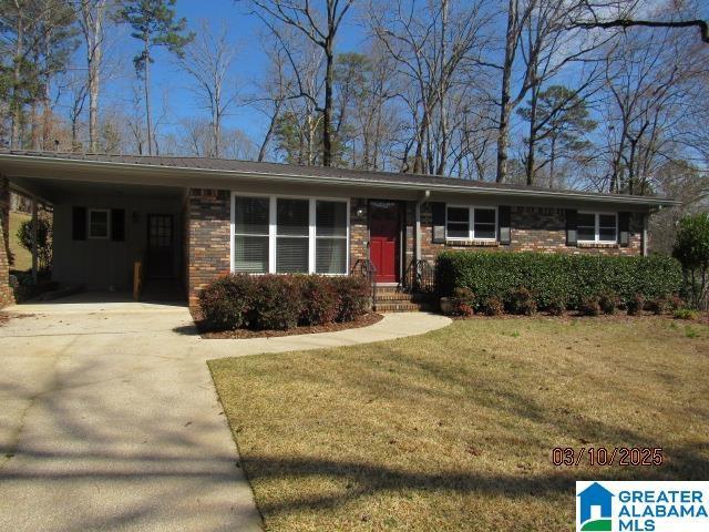 single story home with brick siding, an attached carport, concrete driveway, and a front yard