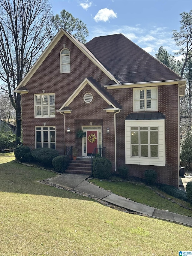 traditional home featuring a front lawn and brick siding