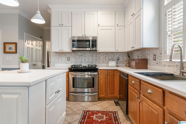 kitchen featuring stainless steel appliances, crown molding, light countertops, and a sink