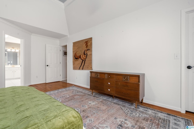 unfurnished bedroom with baseboards, wood finished floors, ensuite bathroom, and ornamental molding