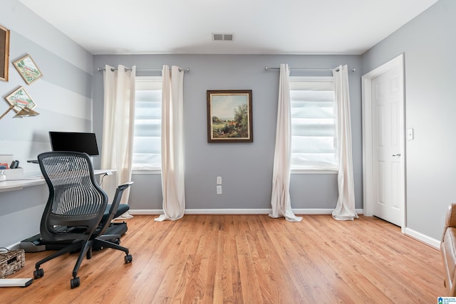 office with wood finished floors, a healthy amount of sunlight, visible vents, and baseboards