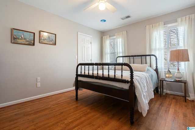 bedroom with visible vents, ceiling fan, baseboards, and wood finished floors