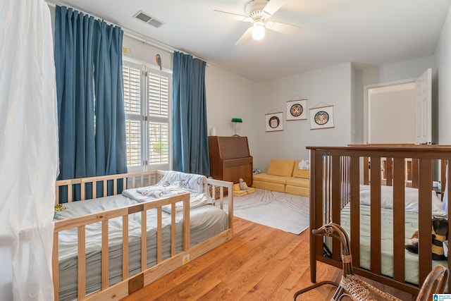 bedroom with a ceiling fan, wood finished floors, and visible vents